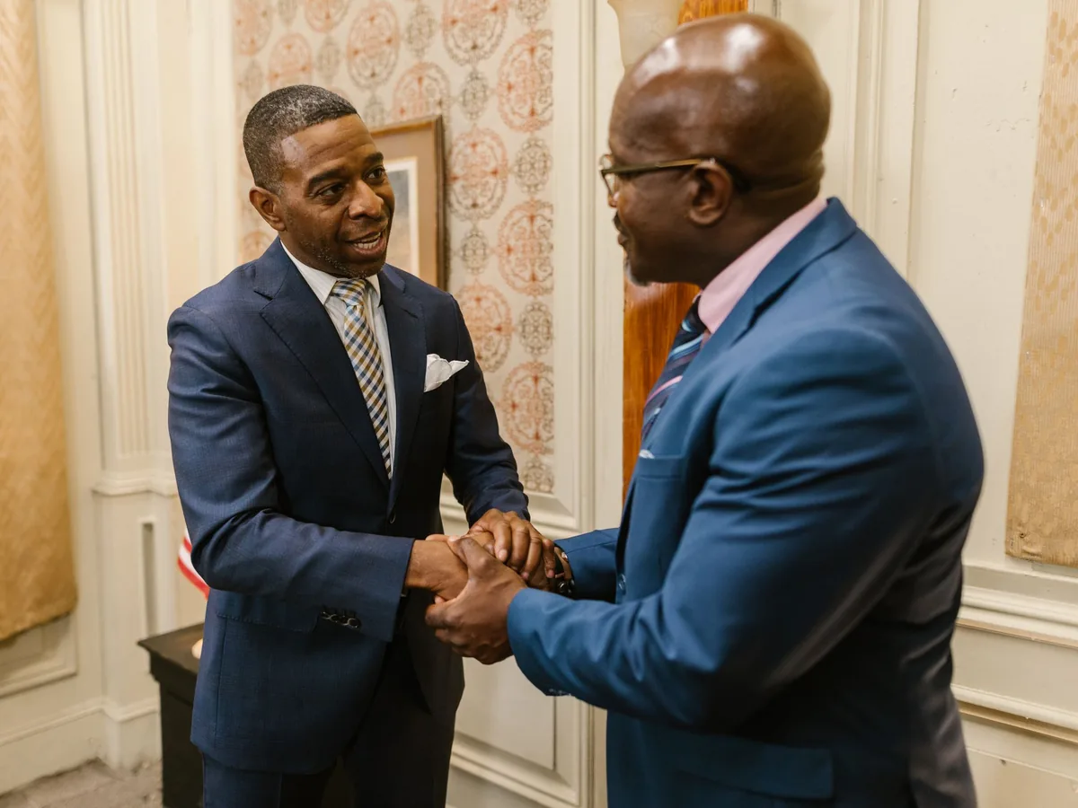 Two men in suits clasping hands as they talk